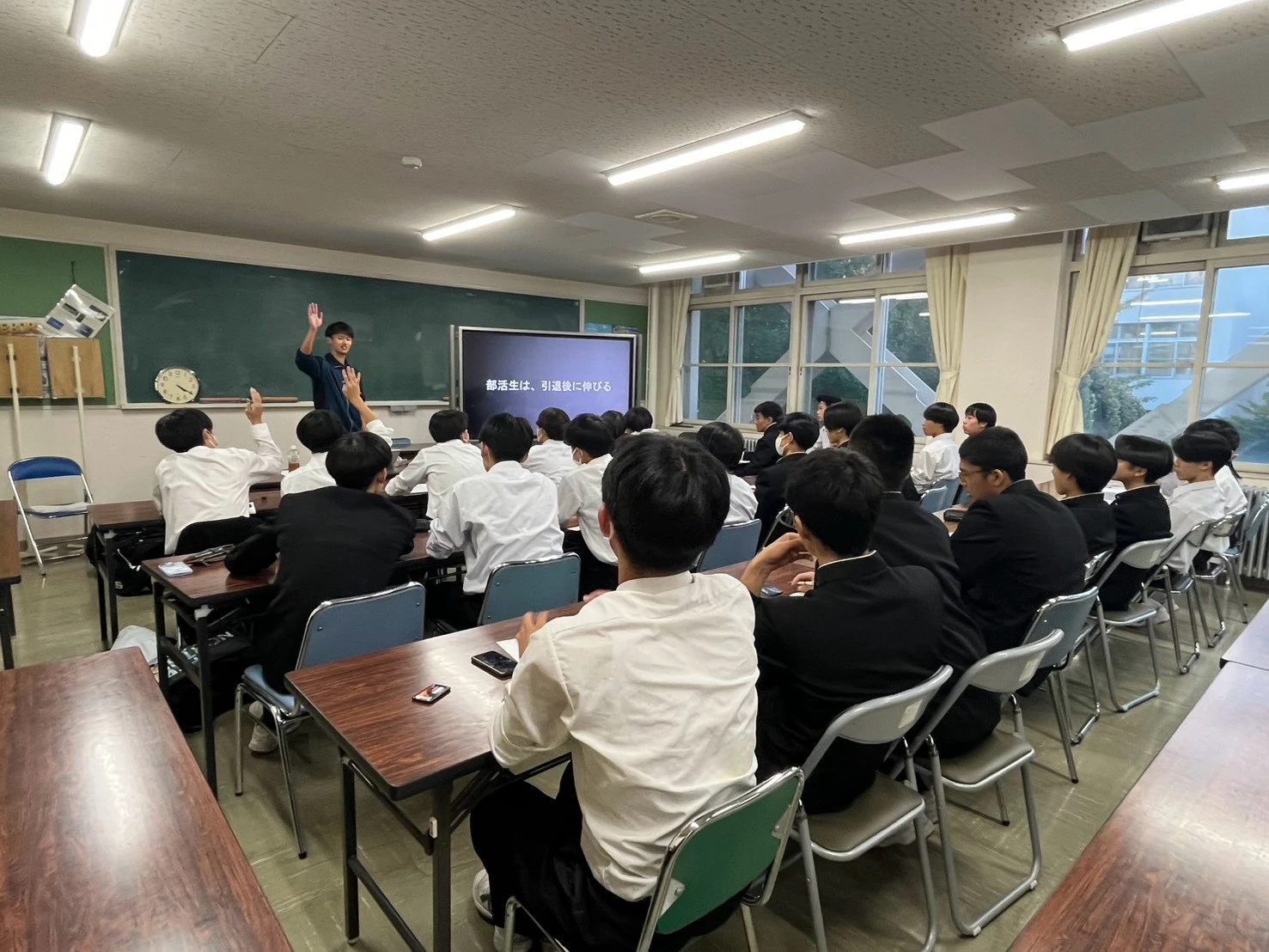 「部活生は、引退後に伸びる」のスライドの前で生徒に問いかける森と、手を挙げる生徒たち