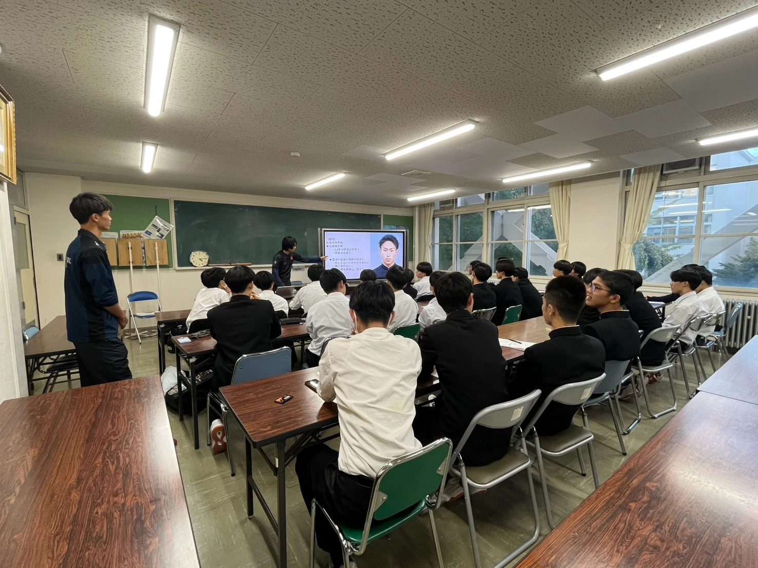 自身の経歴をスライドに映して話す志村さんと聴講する月寒高校サッカー部の生徒たち